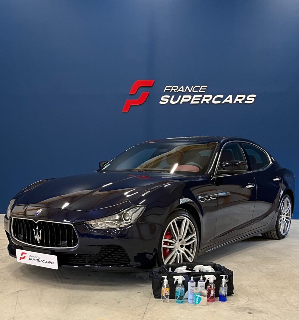 Une voiture Maserati dans le showroom France Supercars, avec un kit de produits d'entretien professionnels à ses côtés.